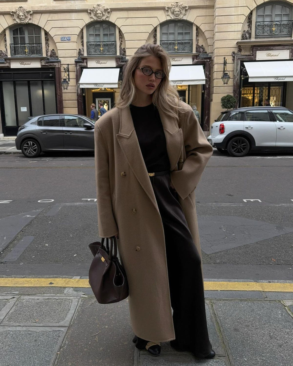 Full-length styling of the brown Manhattan Tote with a camel coat