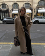 Full-length styling of the brown Manhattan Tote with a camel coat