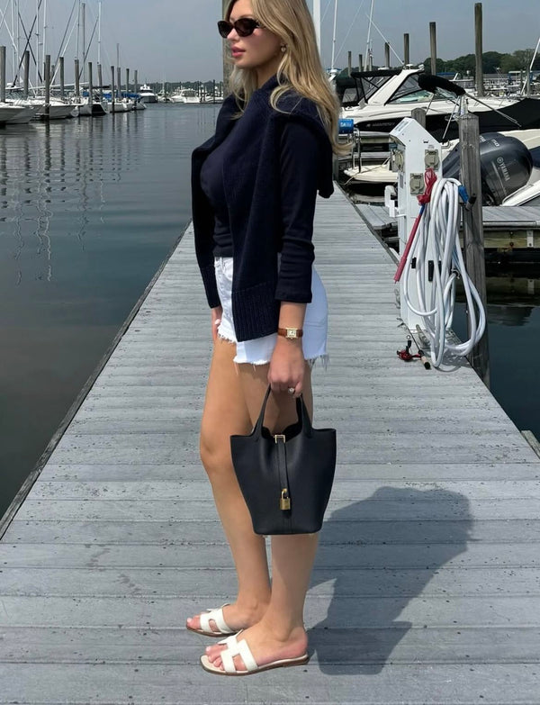 woman carrying black mini tote bag at a marina