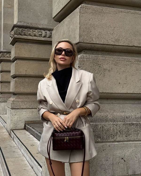 woman in beige blazer carrying burgundy woven mini bag