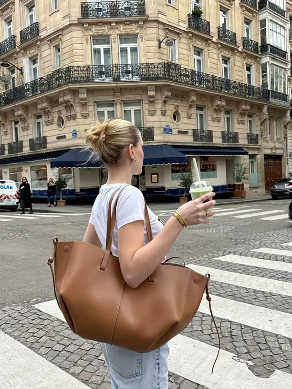 woman carrying tan winged tote bag on a Paris street