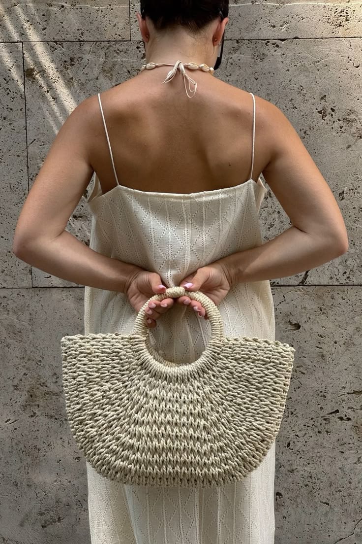 woman carrying cream crescent straw bag with summer dress
