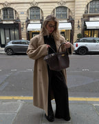 Woman opening the brown Manhattan Tote while standing on a city street