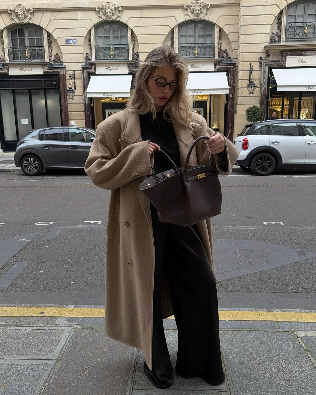 Woman opening the brown Manhattan Tote while standing on a city street