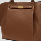 Close-up of brown Manhattan Tote with gold-tone clasp and stitching