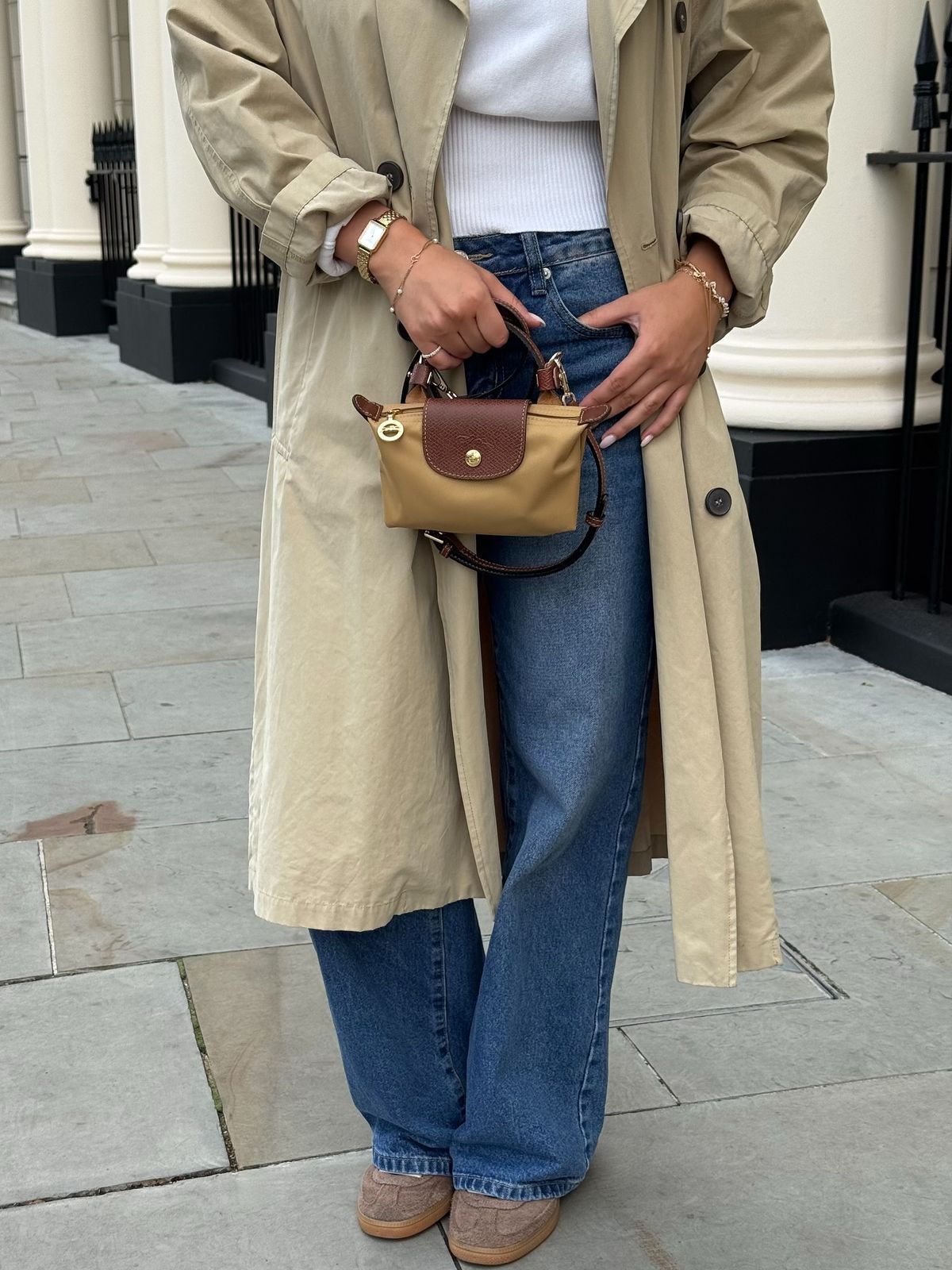 Le Pliage Mini Pouch in Caramel carried by hand with a trench coat