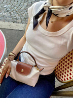 Le Pliage Mini Pouch in Paper beige styled at an outdoor café