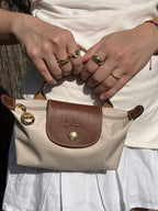 Le Pliage Mini Pouch in Paper beige carried by the top handle