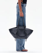 women carrying black knotted tote bag by hand street style