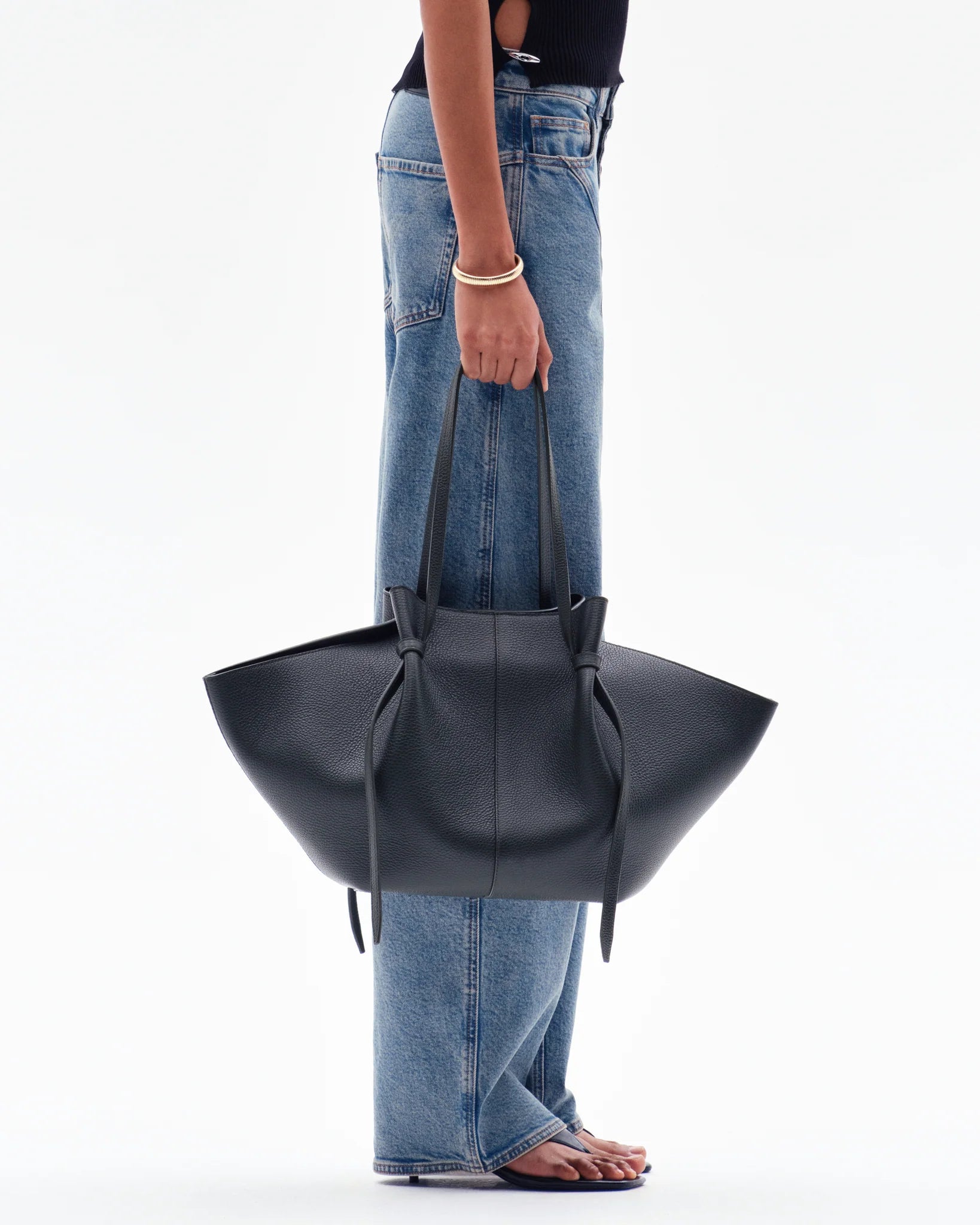 women carrying black knotted tote bag by hand street style