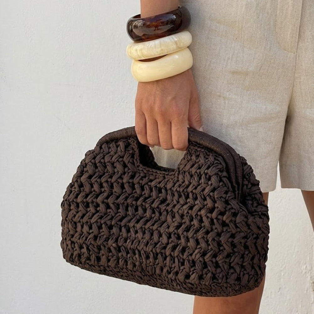 woman hand gripping brown crochet clutch bag resin bangles linen shorts - brown - clutch bag