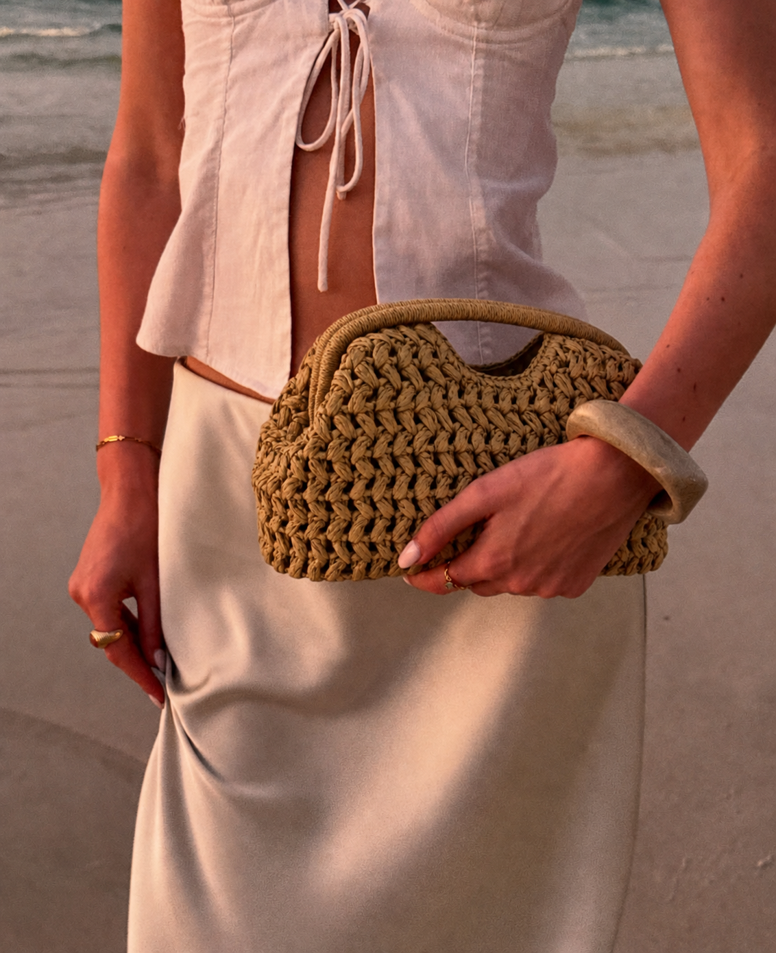 woman holding natural woven clutch bag with summer outfit