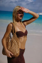 model holding wooden bead tote bag on beach shielding sun natural tan - tan - tote bag