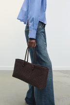 women carrying woven tote bag burgundy street style side